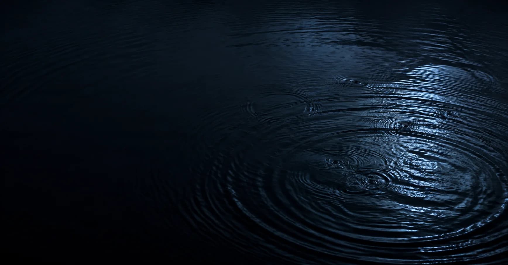 Concentric ripples meeting across dark water